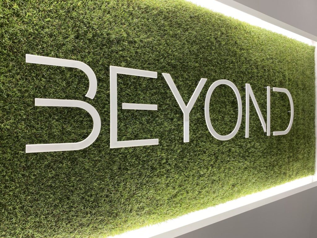 BEYOND巣鴨店のロゴ看板。人工芝の背景に白い立体文字でデザインされた店内装飾